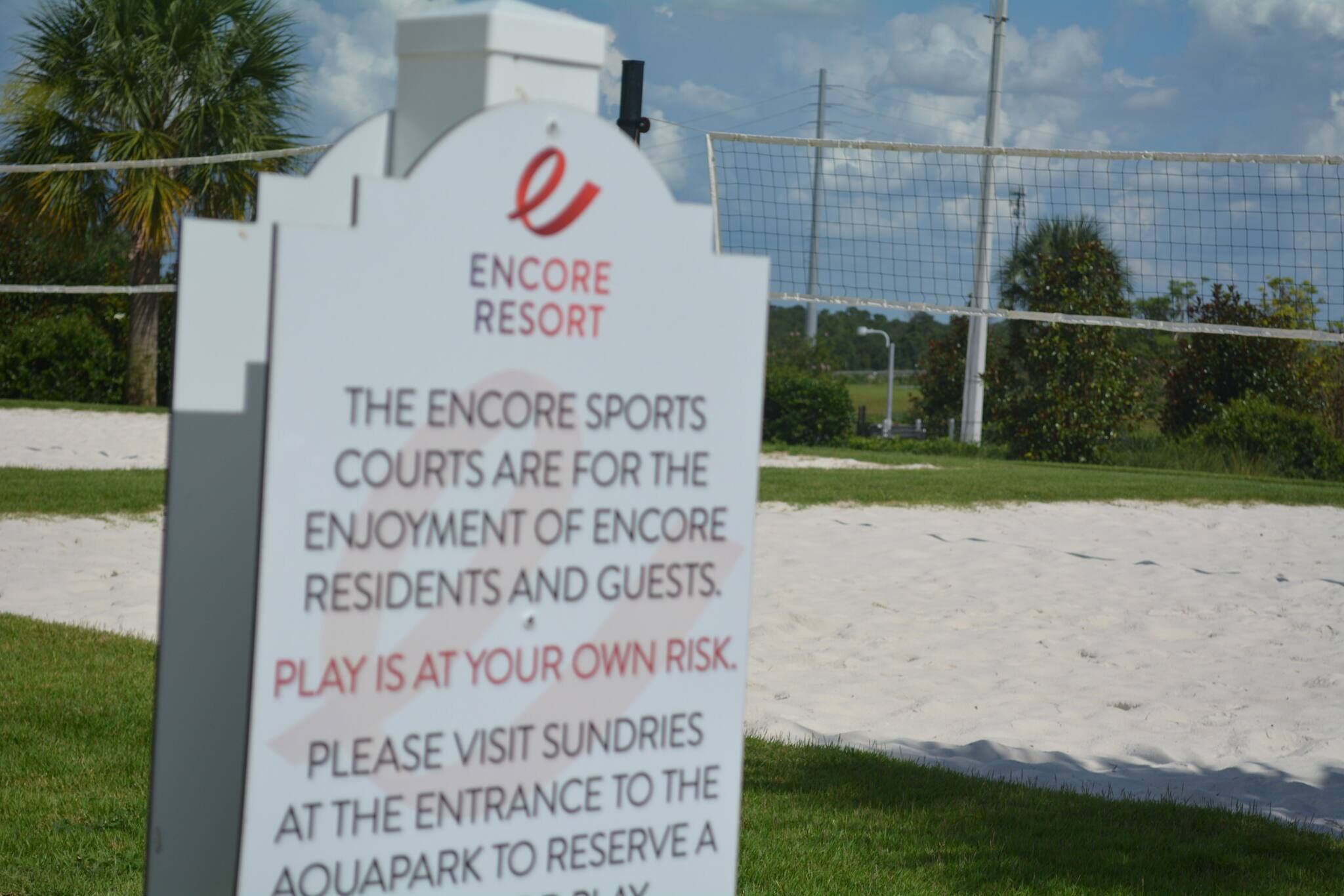 A sign at Encore Resort indicating the sports courts are for resident and guest enjoyment, with a disclaimer about playing at one's own risk.