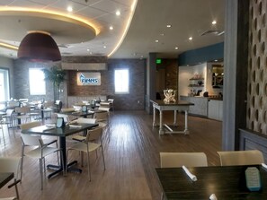 A spacious restaurant with a modern interior, featuring a prominent 'FINNS' sign on the wall, wooden flooring, and a mix of table and chair arrangements. - Disney Dreams Luxury Home With Private Water Park (Kissimmee)