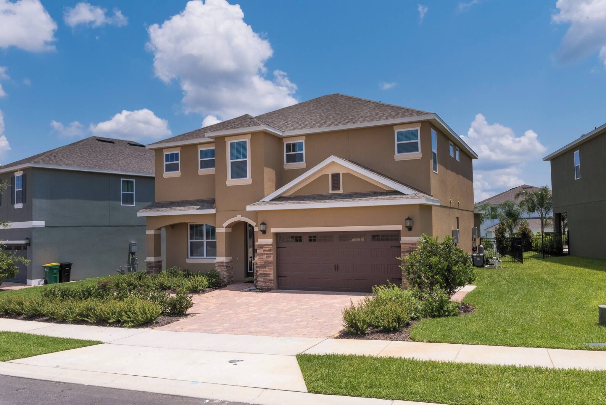 A two-story residential building with a garage, a driveway, and a well-maintained lawn.