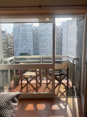 A balcony with a table and chairs, a potted plant, and a view of surrounding buildings. - Studio apartment in the Guemes-Aldrey area (Mar del Plata)