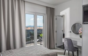 A modern hotel room with a bed, a desk, a chair, a round mirror, and a balcony with a view. - Lovely home in Zadar with sauna (Zadar)