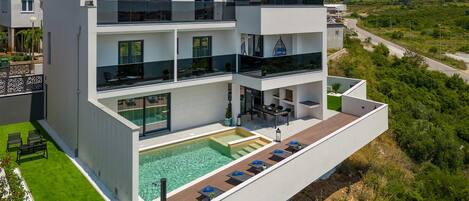 Un edificio moderno de varios pisos con piscina en la azotea y zona de estar al aire libre.