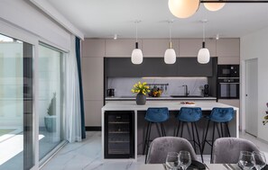 A modern kitchen with a central island, bar stools, and pendant lighting. - Lovely home in Zadar with sauna (Zadar)