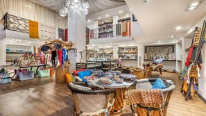 Interior espaçoso de um hotel boutique, com área de estar central, diversas mesas de exposição e vários artigos à venda.