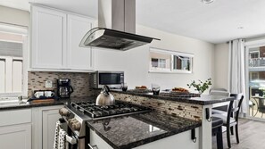 Una cocina moderna con una isla central, estufa integrada, cafetera y microondas.