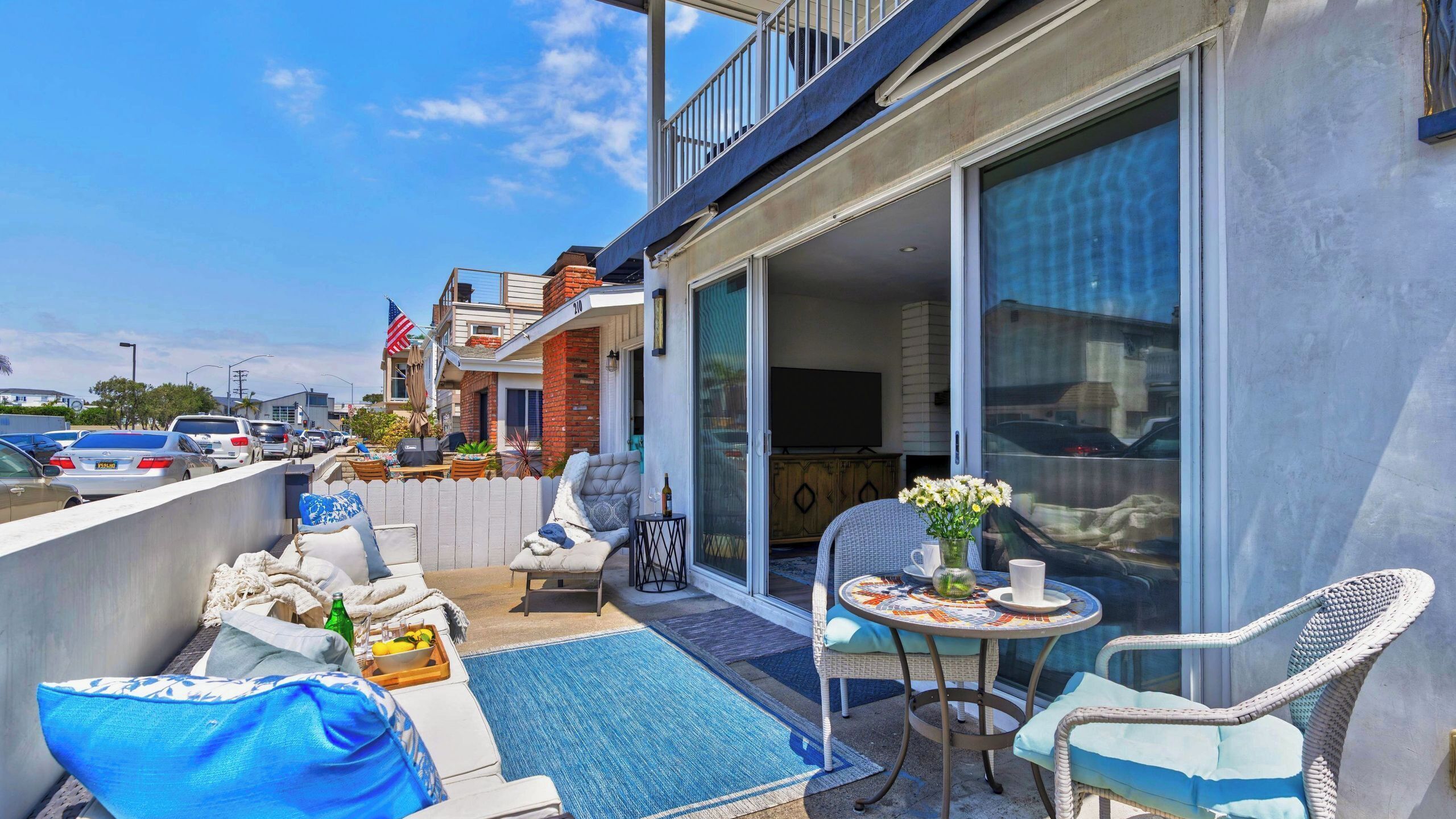 Un balcon avec coin salon extérieur, une télévision et vue sur la rue.