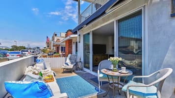 A balcony with outdoor seating, a TV, and a view of the street.