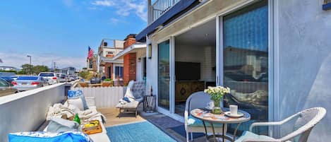 Un balcon avec coin salon extérieur, une télévision et vue sur la rue.