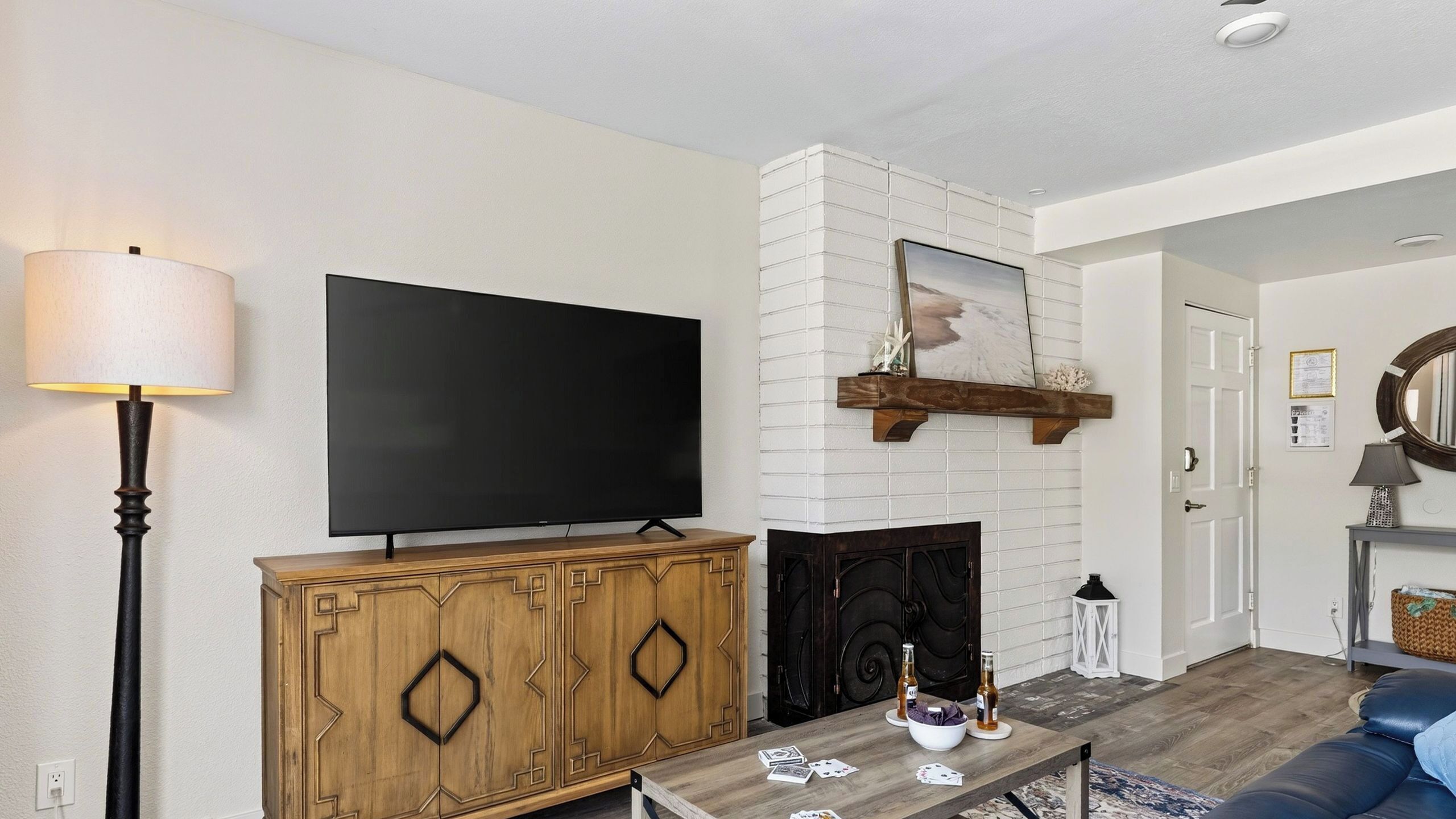 A living room with a flat-screen TV, a fireplace, a wooden cabinet, and a coffee table with books and a bowl.