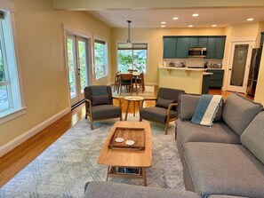 A modern living room with a sofa, chairs, a coffee table, and a dining area. - Forest Retreat | Hot Tub & Sauna (Bellingham)