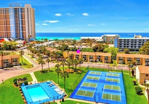 Ein Hotel mit mehreren Tennisplätzen, einem Swimmingpool und Blick auf den Ozean.