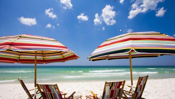 Uma praia com dois guarda-sóis listrados e cadeiras de praia.