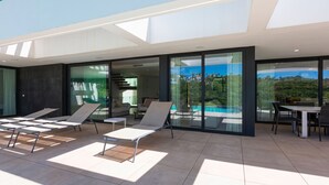 A modern outdoor patio with lounge chairs, a dining table, and a view of a swimming pool and greenery. - The Solstice Estate – Private Pool Retreat for Families & Groups (Marbella)
