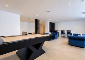 A modern living room with a pool table, blue sofas, and a bar area. - The Solstice Estate – Private Pool Retreat for Families & Groups (Marbella)