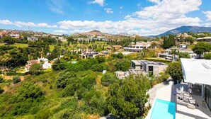 A residential area with a modern house featuring a swimming pool, surrounded by lush greenery and a clear blue sky. - The Solstice Estate – Private Pool Retreat for Families & Groups (Marbella)