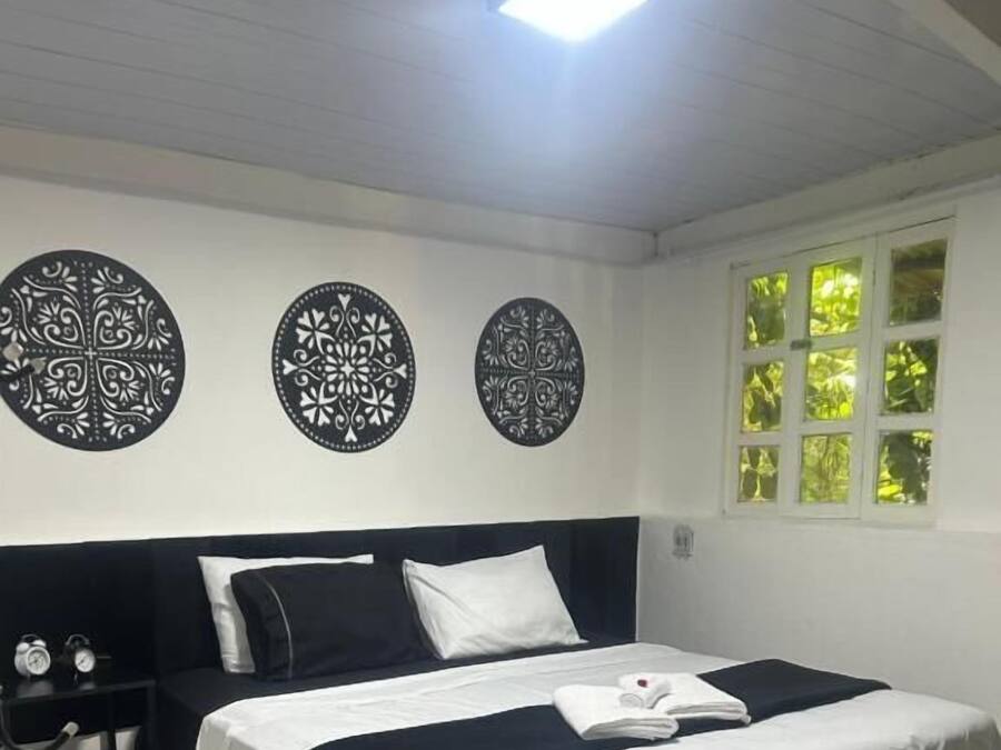 A bedroom with a bed, a nightstand, a black rug, and decorative wall art.