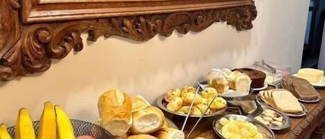 A buffet table with various food items and a mirror reflecting a Buddha statue and a clock.