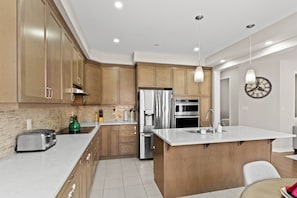 Una cocina moderna con armarios de madera, electrodomésticos de acero inoxidable y una isla central.