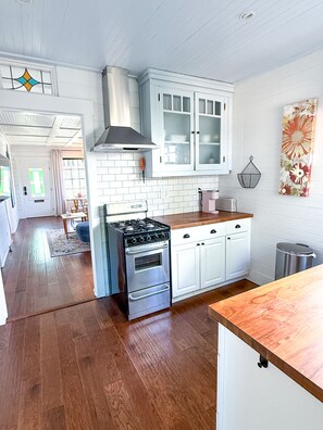 A kitchen with white cabinets, a stainless steel stove, and wooden flooring. - Rosé Chalet (San Diego)