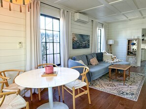 A room with a round table, chairs, a sofa, a rug, and a cabinet with a mirror. - Rosé Chalet (San Diego)