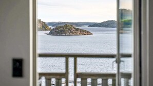 Vista de águas calmas com uma pequena ilha e formações terrestres ao longe.