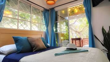 A bedroom with a large bed, a wooden headboard, and a view of greenery outside.