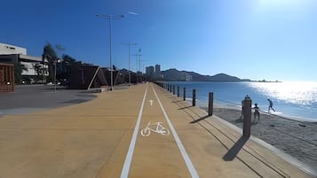 Un paseo marítimo con una ciclovía, una playa y una vista despejada del mar.
