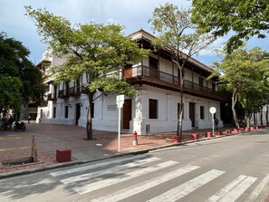 A building with a balcony, a street in front, and trees. - Apto Centro Histórico Balcón (Santa Marta)