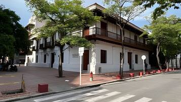 A two-story building with a white facade, wooden balconies, and a red brick ground floor.