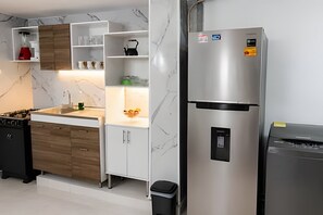 A modern kitchen with a stainless steel refrigerator, wooden cabinets, and a marble backsplash.