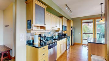 A modern kitchen with wooden cabinets, a stainless steel dishwasher, and a large window.