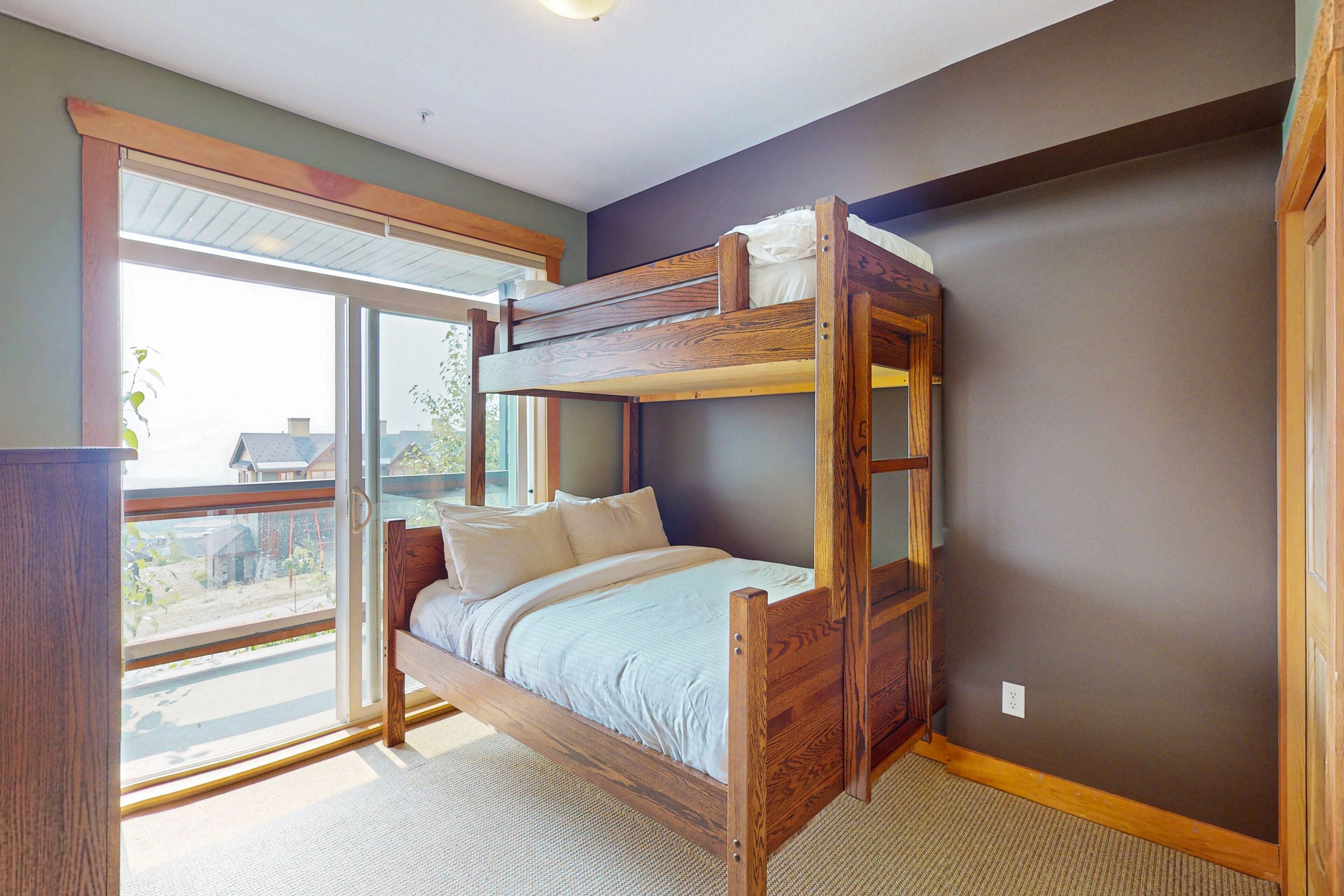 A bunk bed with a view of the outdoors through a large window.