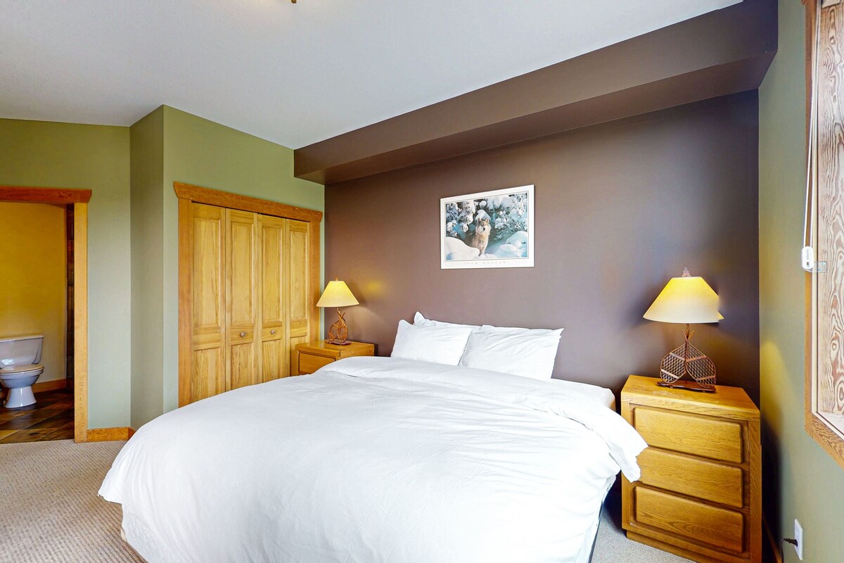 A bedroom with a large bed, wooden nightstands, a wooden wardrobe, and a framed picture on the wall.