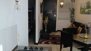 Eine moderne Küche mit Gasherd, ein Essbereich mit Tisch und Stühlen sowie ein Wohnzimmer mit Sofa und einem Bild an der Wand.