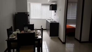 Eine kleine Küche mit Essbereich, einem Fenster und einem Bett im angrenzenden Raum.