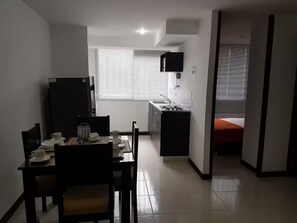 A compact kitchen with a dining area, a small window, and a bed in the adjacent room. - Lindo Apartamento amoblado a minutos de sitios turisticos (Montenegro Province)