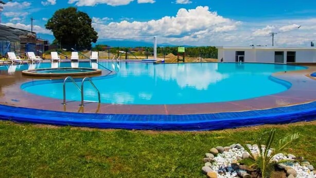 Ein Schwimmbecken mit Liegestühlen und einem Gebäude im Hintergrund.