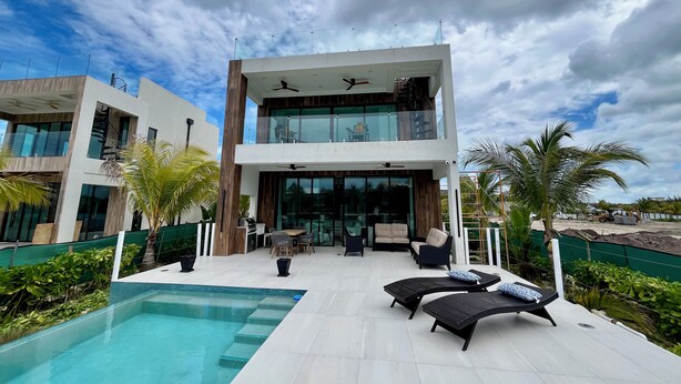 A modern two-story house with a swimming pool, outdoor seating, and a view of the sky. - Luxury 2026 Waterfront Home w/ Yacht Dock + Rooftop (Freeport)