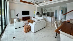 A spacious living area with a white sofa set, a wooden coffee table, and a TV mounted on the wall. - Luxury 2026 Waterfront Home w/ Yacht Dock + Rooftop (Freeport)