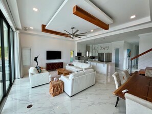 A spacious living area with a white sofa set, a wooden coffee table, and a TV mounted on the wall. - Luxury 2026 Waterfront Home w/ Yacht Dock + Rooftop (Freeport)