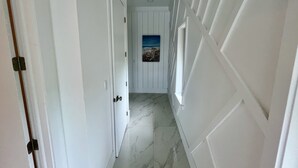 A hallway with white doors, a marble floor, and a framed picture on the wall. - Luxury 2026 Waterfront Home w/ Yacht Dock + Rooftop (Freeport)