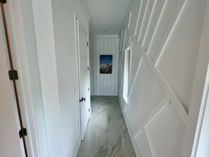 A hallway with white doors, a marble floor, and a framed picture on the wall. - Luxury 2026 Waterfront Home w/ Yacht Dock + Rooftop (Freeport)