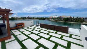 A rooftop terrace with a view of a body of water, a wooden pergola, and a patterned floor. - Luxury 2026 Waterfront Home w/ Yacht Dock + Rooftop (Freeport)