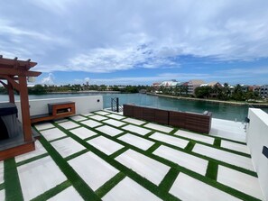 A rooftop terrace with a view of a body of water, a wooden pergola, and a patterned floor. - Luxury 2026 Waterfront Home w/ Yacht Dock + Rooftop (Freeport)