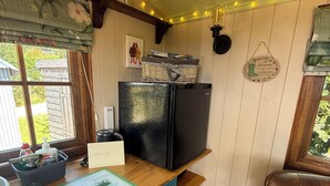 Una cocina con un refrigerador negro, una encimera de madera y una ventana con cortinas.