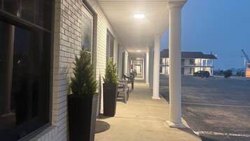A hotel corridor with a sign indicating a breakfast room, potted plants, and a parking lot in the background.