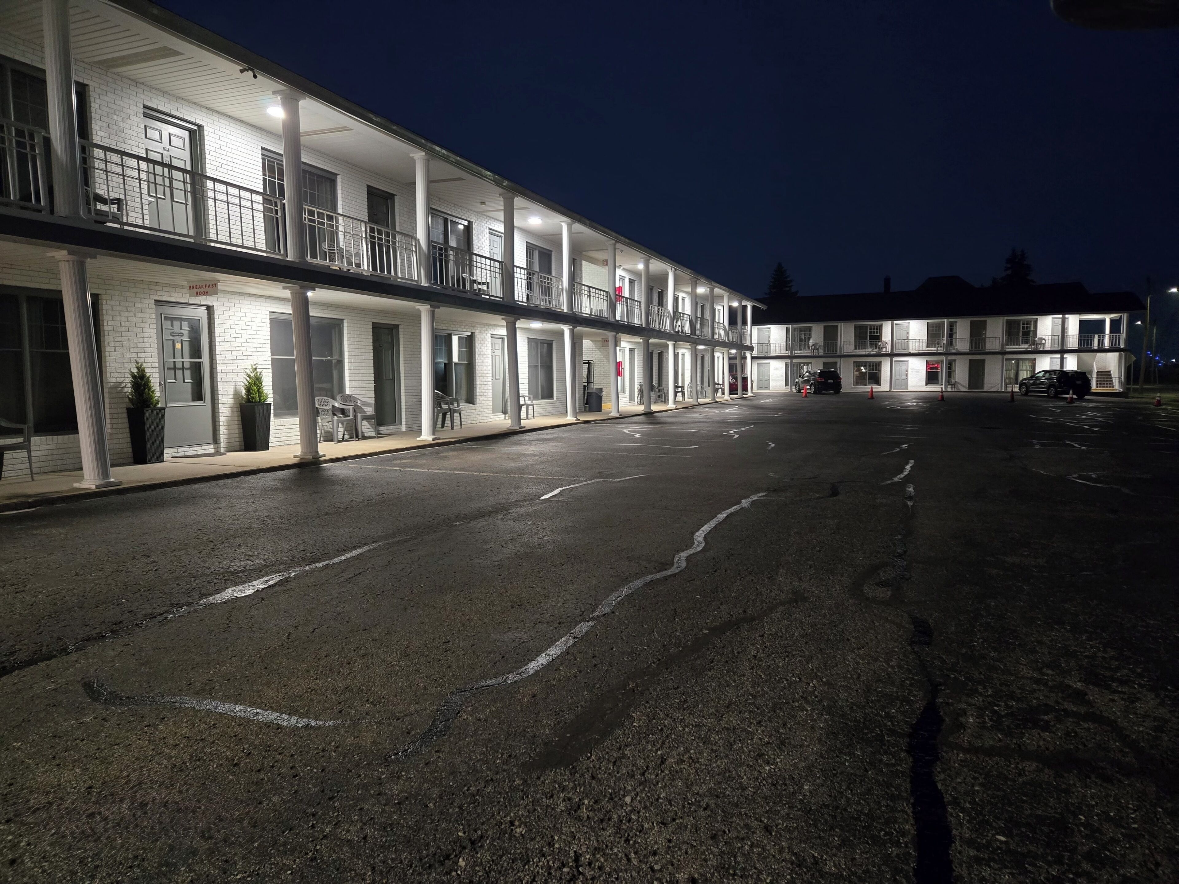 A motel with multiple rooms, a covered parking area, and a well-lit facade at night.