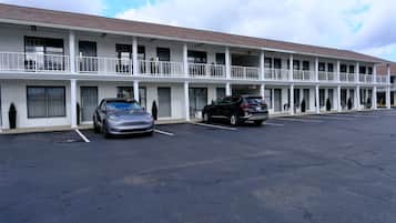 A motel with a two-story structure, a covered parking area, and a clear sky.
