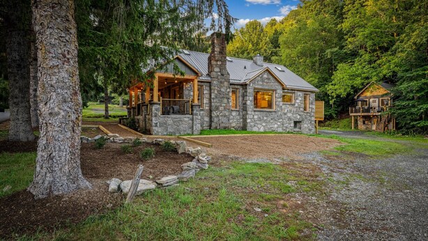 A stone cabin with a porch, surrounded by a forested area. - Historic Hodge House|2BD•2BA|King Beds| Sleeps 6 (Banner Elk)
