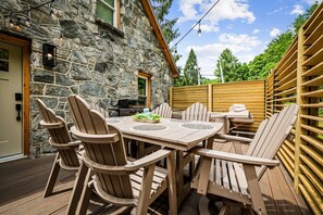 A stone building with a wooden deck, outdoor seating, and a grill. - Historic Hodge House|2BD•2BA|King Beds| Sleeps 6 (Banner Elk)